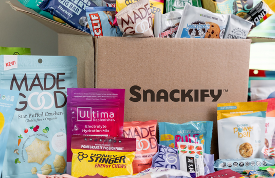 Snackify box with various snack packets including Made Good, Ultima, and Honey Stinger.